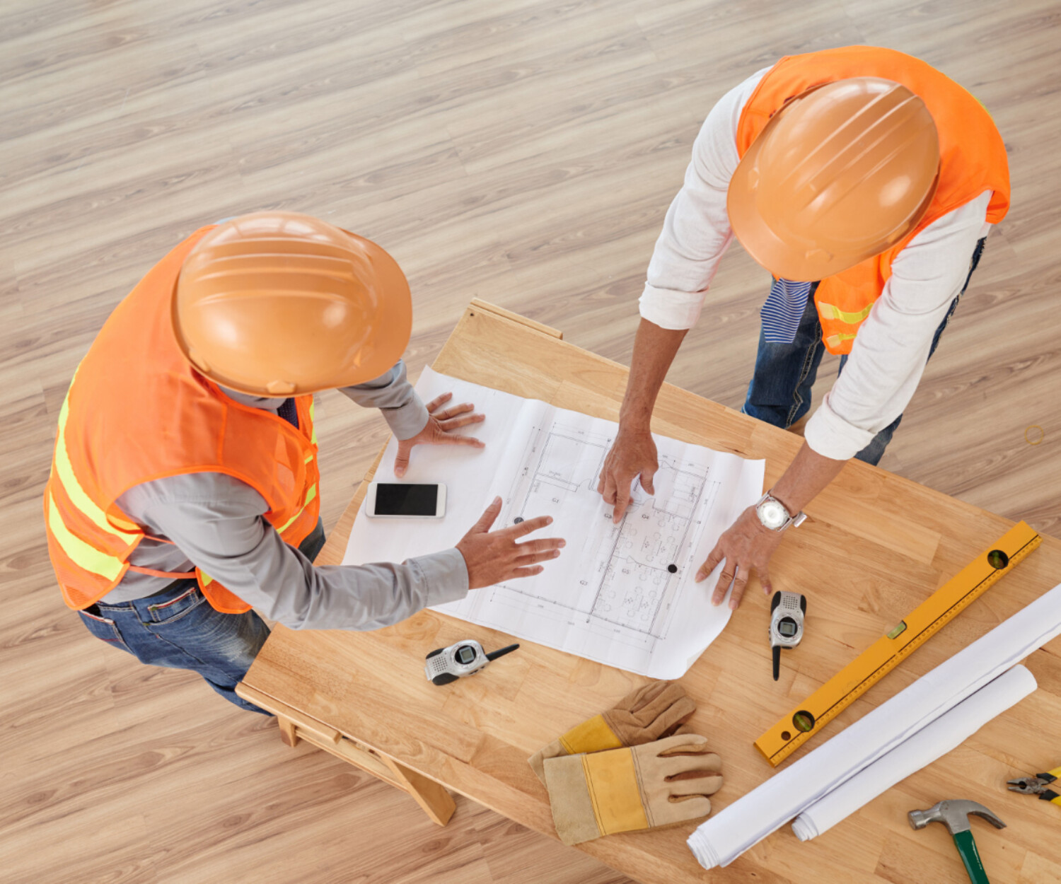 altier-avocat gironde, deux professionnels du bâtiment analysent un plan de construction avec outils de chantier