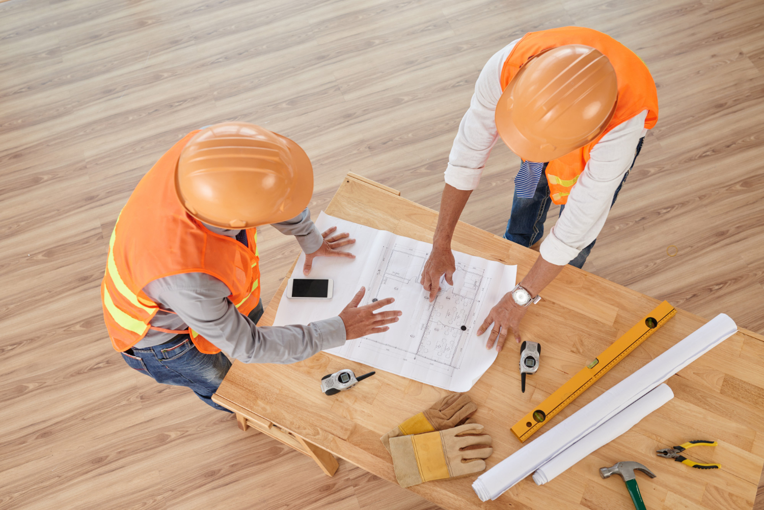 altier-avocat gironde, deux professionnels du bâtiment analysent un plan de construction avec outils de chantier